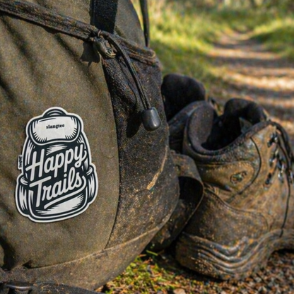Hiking backpack and boots with 'Happy Trails' logo on a forest path