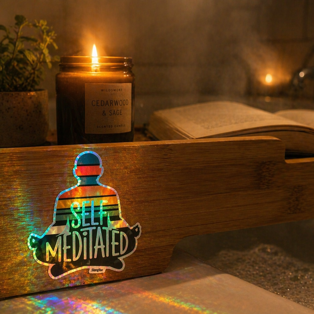 Wooden sign with 'Self Meditated' design, lit candle, and open book in a cozy setting.